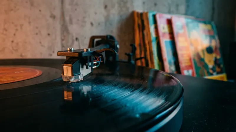 A high-fidelity macro shot of a vintage vinyl record spinning on a modern turntable, with the record's surface reflecting a soft, warm orange and blue light.